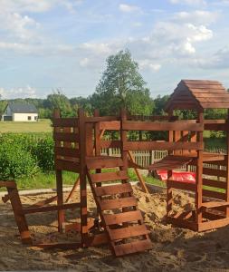 two wooden benches sitting in the sand with a gazebo at Przylesie in Uniejow +9 photos