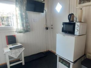 a small room with a refrigerator with a microwave on top of it at Gæstehus Stillinge Strand in Stillinge Strand +15 photos
