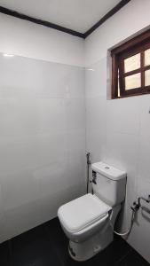 a white bathroom with a toilet and a window at B&B Nuwara eliya in Nuwara Eliya +63 photos