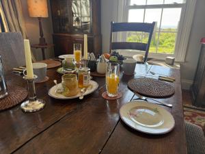 a wooden table with plates and glasses of orange juice at Cottage on remote wild coast in Bawdsey