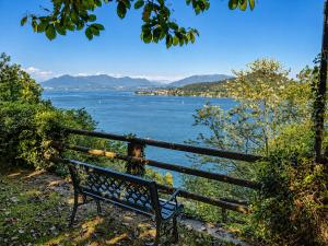 a woman sitting on a bench looking at the water at Villa Romilda in Arona