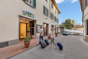 a man and woman walking down a street with their luggage at B&B Il Connubio - Rooms & Apt between Florence and Chianti in Impruneta