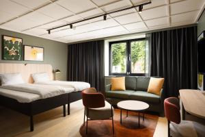 a bedroom with a bed and a couch and a chair at Scandic Neptun in Bergen