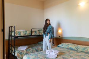 a woman standing in a room with two bunk beds at Hotel Diplomatic - Bianchi Hotels in Cesenatico +80 photos