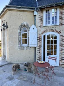 two dogs sitting in front of a house with a table at Le Grand Clos Marçon in Marçon