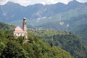 a building on a hill with mountains in the background at salvia in Arta Terme