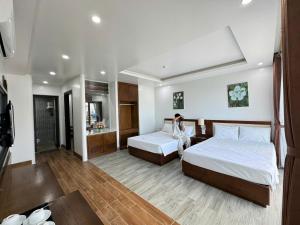 a woman sitting on a bed in a hotel room at Sen Biển Hotel Luxury Sầm Sơn in Sầm Sơn