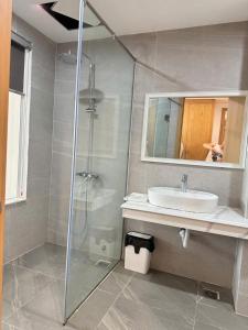 a bathroom with a shower and a sink and a mirror at Sen Biển Hotel Luxury Sầm Sơn in Sầm Sơn +9 photos