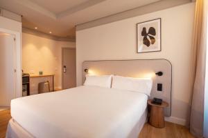 a bedroom with a large white bed and a table at Petit Palace Preciados in Madrid +90 photos
