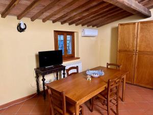 a dining room with a wooden table and a television at Nido in Toscana - Appartamento in Centro Storico con Aria Condizionata in Buonconvento