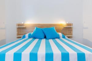 a bed with blue pillows in a room at Vidamarina - Camere al Mare in Torre Lapillo