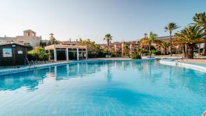 a large blue swimming pool with palm trees and buildings at Hotel Bahia Sur in San Fernando
