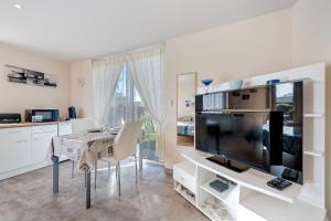 a kitchen with a dining table and a large television at Chambre d'hote chez Odile in Plougoulm