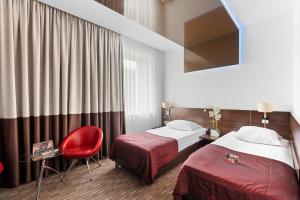 a hotel room with two beds and a red chair at Park Hotel Diament Zabrze - Gliwice in Zabrze +75 photos