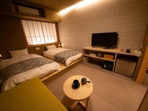 a room with two beds and a tv and a table at Sunriver Oboke in Miyoshi +25 photos