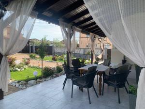 a patio with a table and chairs and curtains at CASA LUI MOȘU in Alba Iulia