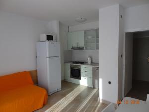 Il comprend une cuisine équipée d'un réfrigérateur blanc et d'un canapé orange. dans l'établissement Holiday House Zorra, à Živogošće