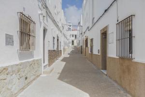 an empty alley with white buildings and a blue sky at Isabel Casa del Mar in Conil de la Frontera