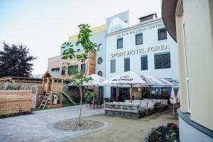 ein Gebäude mit Tischen und Sonnenschirmen in einem Innenhof in der Unterkunft Hotel Forea in Lanškroun