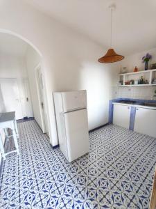a kitchen with a white refrigerator and blue and white tiles at La casita in Capo Vaticano