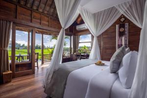 a bedroom with a white bed with a view at Berlima Boutique Resort in Ubud