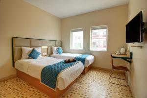 a hotel room with two beds and a flat screen tv at Hotel Vilmaris Breeze in Calangute