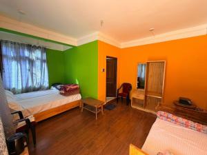 a room with two beds and an orange and green wall at Sangha Homestay in Dirang Dzong