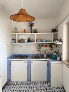 a small kitchen with white cabinets and blue tiles at La casita in Capo Vaticano