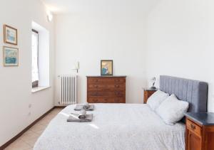 a white bedroom with a bed and a dresser at La Terrazza sul Giardino in Asti
