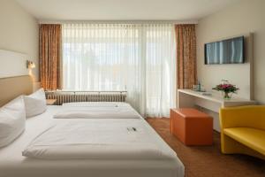 a hotel room with two beds and a window at LU8 Business Vital Hotel in Bad Dürrheim