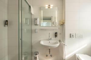 a bathroom with a sink and a glass shower at LU8 Business Vital Hotel in Bad Dürrheim +53 photos