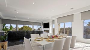 a dining room with a white table and white chairs at The Coral Esplanade in Mornington