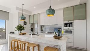 a kitchen with a large marble counter and wooden chairs at The Coral Esplanade in Mornington