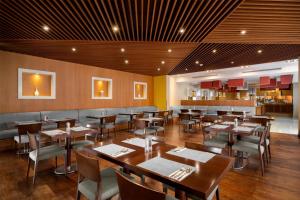 a restaurant with wooden tables and chairs and a bar at Park Inn by Radisson Al Khobar in Al Khobar