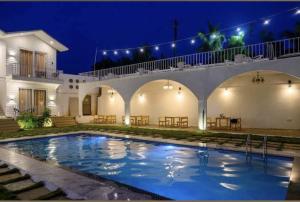 a swimming pool in front of a house at night at Tvessa-A Boutiqe Hotel in Mandrem +13 photos