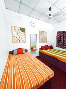 a bedroom with two beds and a clock on the wall at Jayawikrama Cafe and Guest in Matara