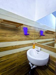 a bathroom with a sink and two purple chairs at Jayawikrama Cafe and Guest in Matara