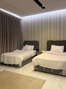 two beds in a hotel room with curtains at رُقيّ للشقق الفندقية rogy VIP in Taif
