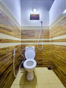 a bathroom with a toilet in a room with wooden walls at Jayawikrama Cafe and Guest in Matara