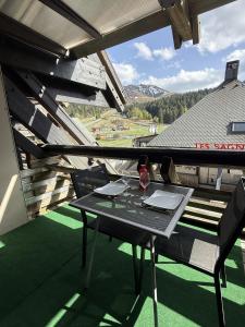 a table with a glass of wine on a balcony at Studio Montagne chic centre station in Le Lioran