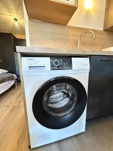 a washing machine in a kitchen with a sink at Studio Montagne chic centre station in Le Lioran