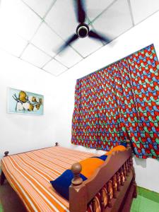 a bedroom with a bed with a curtain on the wall at Jayawikrama Cafe and Guest in Matara