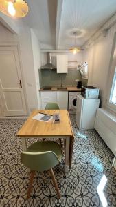 a kitchen with a wooden table and two green chairs at Petit Buragna in Alghero