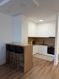 a kitchen with white cabinets and a wooden table and chairs at City Break Sarajevo in Sarajevo