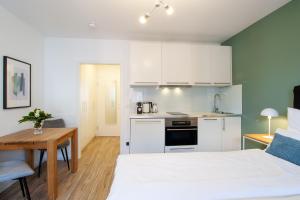 a room with a bed and a table and a kitchen at Sali Homes - Wahnfried No 1 City Apartment Balcony in Bayreuth +8 photos