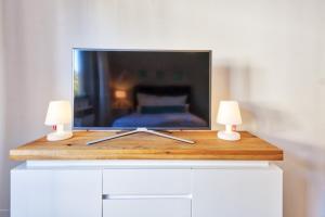 a television on top of a dresser with two lamps at Sali Homes - Wahnfried No 1 City Apartment Balcony in Bayreuth