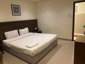 a bedroom with a large bed with white sheets at Hotel Blu Ivy in Chennai