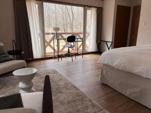 a bedroom with a bed and a table and a couch at Villa Lina - 北軽井沢で四季折々の自然を楽しむプライベート貸別荘 最大6名 in Naganohara