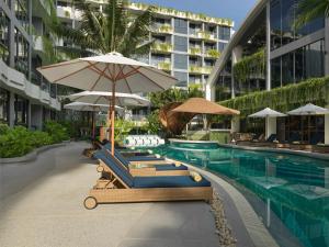 a resort pool with lounge chairs and umbrellas at GreenLa by Villacarte in Layan Beach