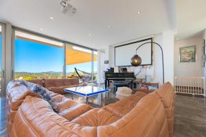 a living room with a leather couch and a piano at Villa Roca Llisa in Santa Eularia des Riu